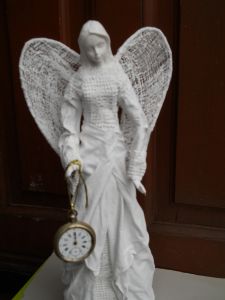 Rzeźba biały anioł trzymający w ręku zegar