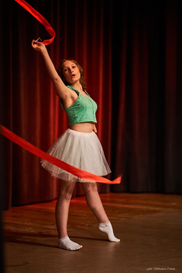 na scenie dziewczyna w pozie tanecznej ze wstążką