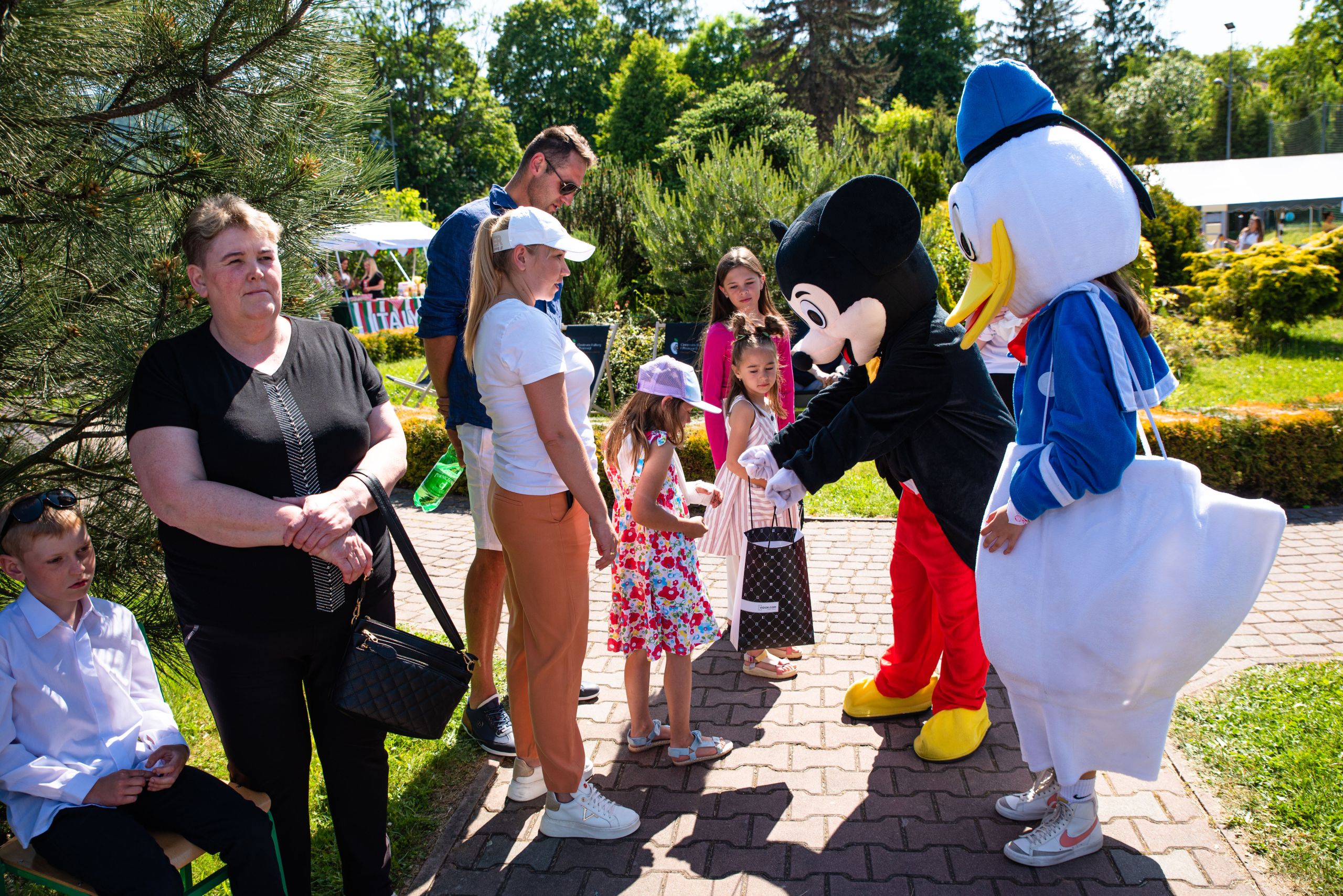 duże maskotki Myszki Miki i Kaczora Donalda rozdają dzieciom cukierki