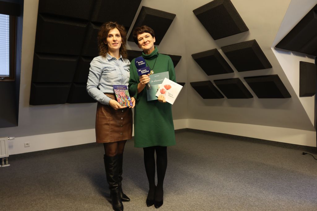 Dwie kobiety pozują do zdjęcia w ręce trzymają książki a jedna z nich mikrofon